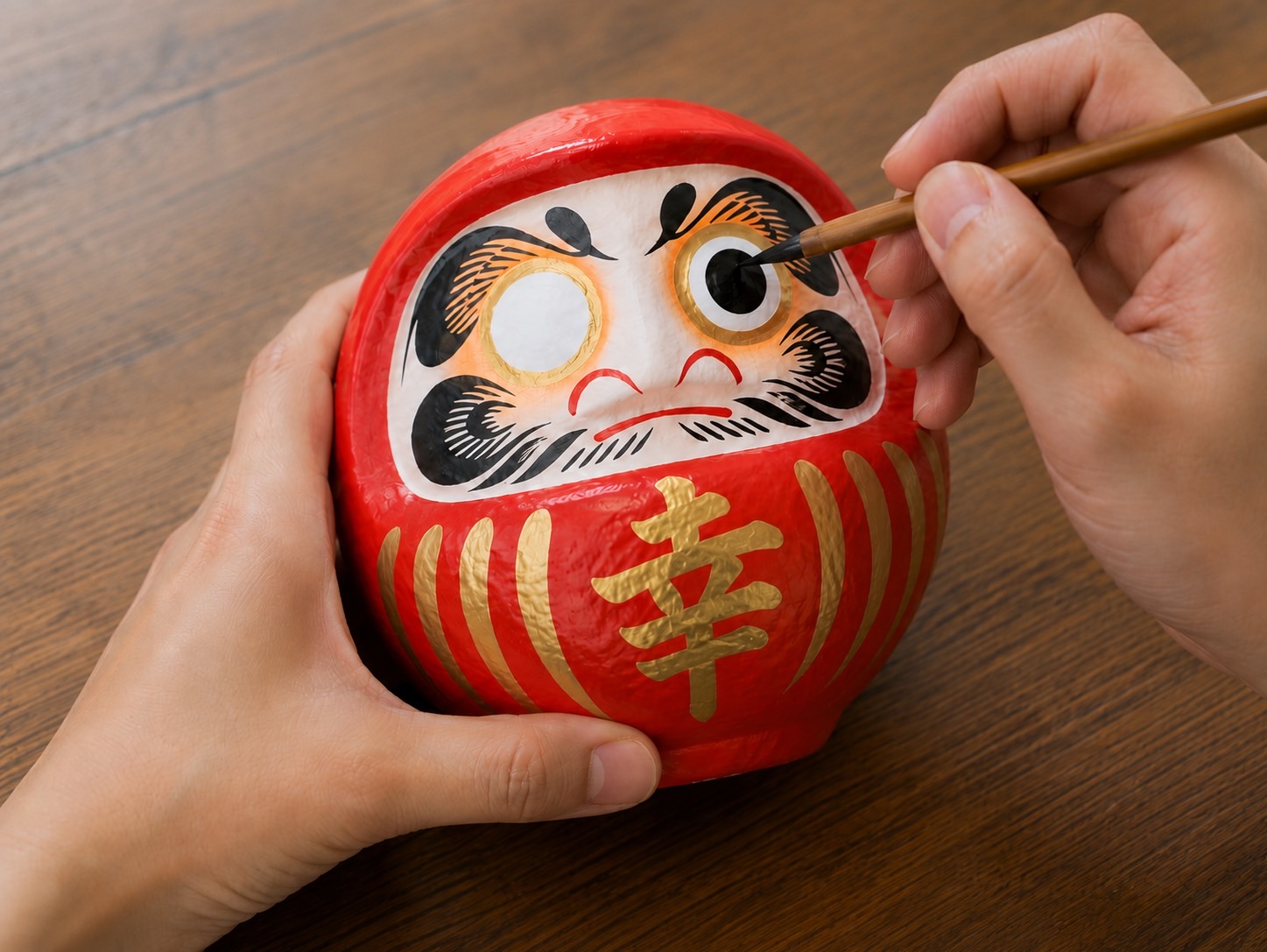 だるまに願いを込めて片目を入れる様子